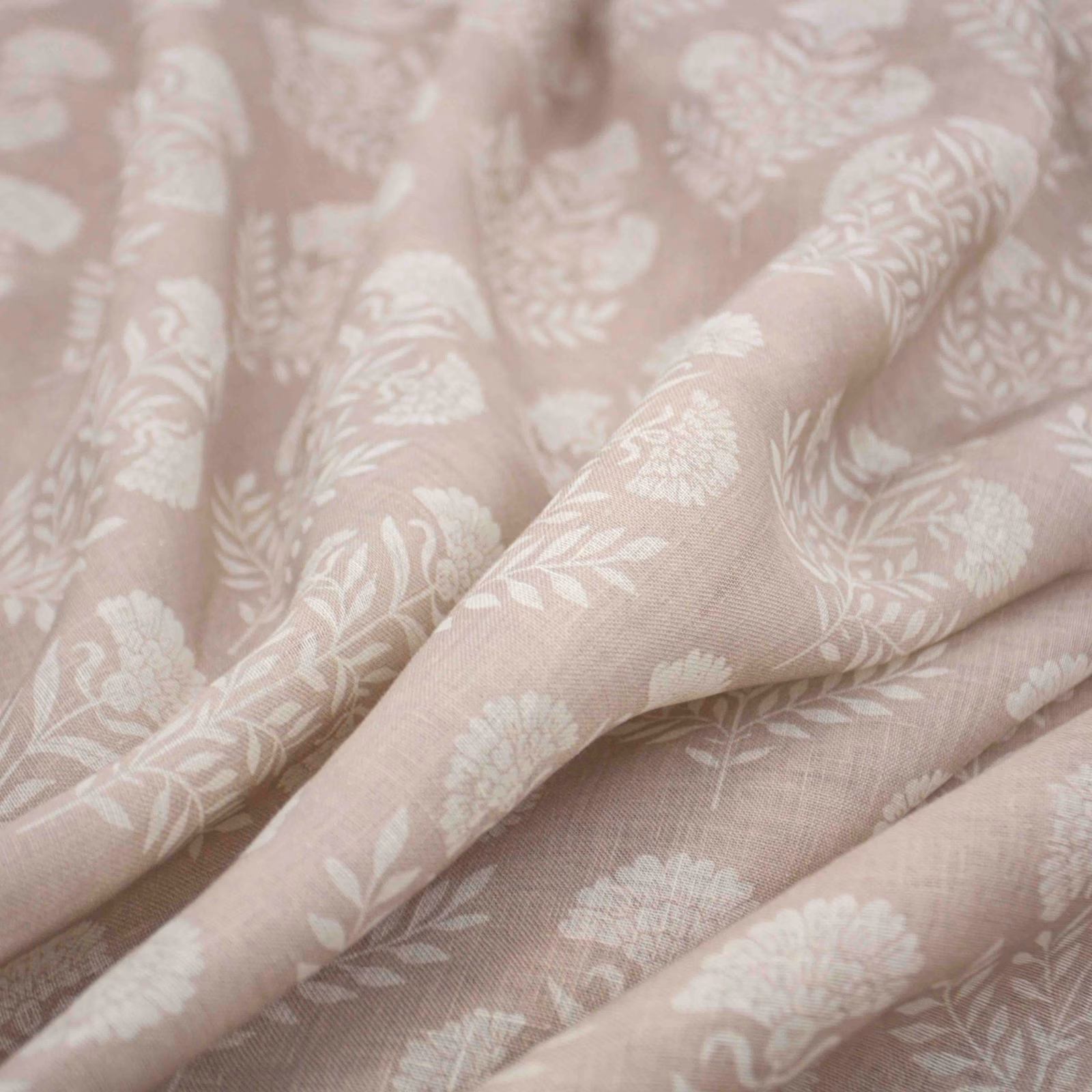 Dusky blush-pink fabric with ivory floral sprays and fine woven texture in soft folds