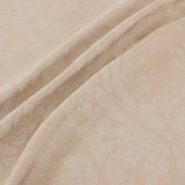 Warm sandstone beige fabric with a subtle woven botanical motif in soft flowing folds