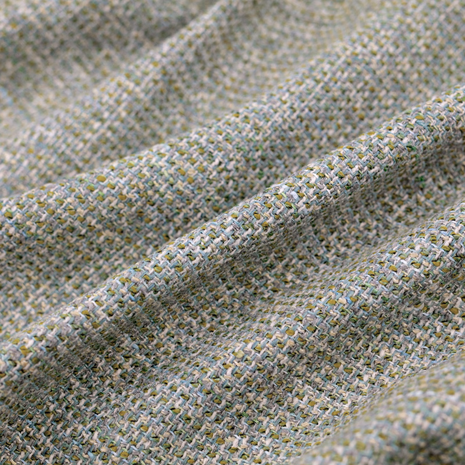 Pale seafoam woven fabric with cream, grey and yellow flecks in soft folds