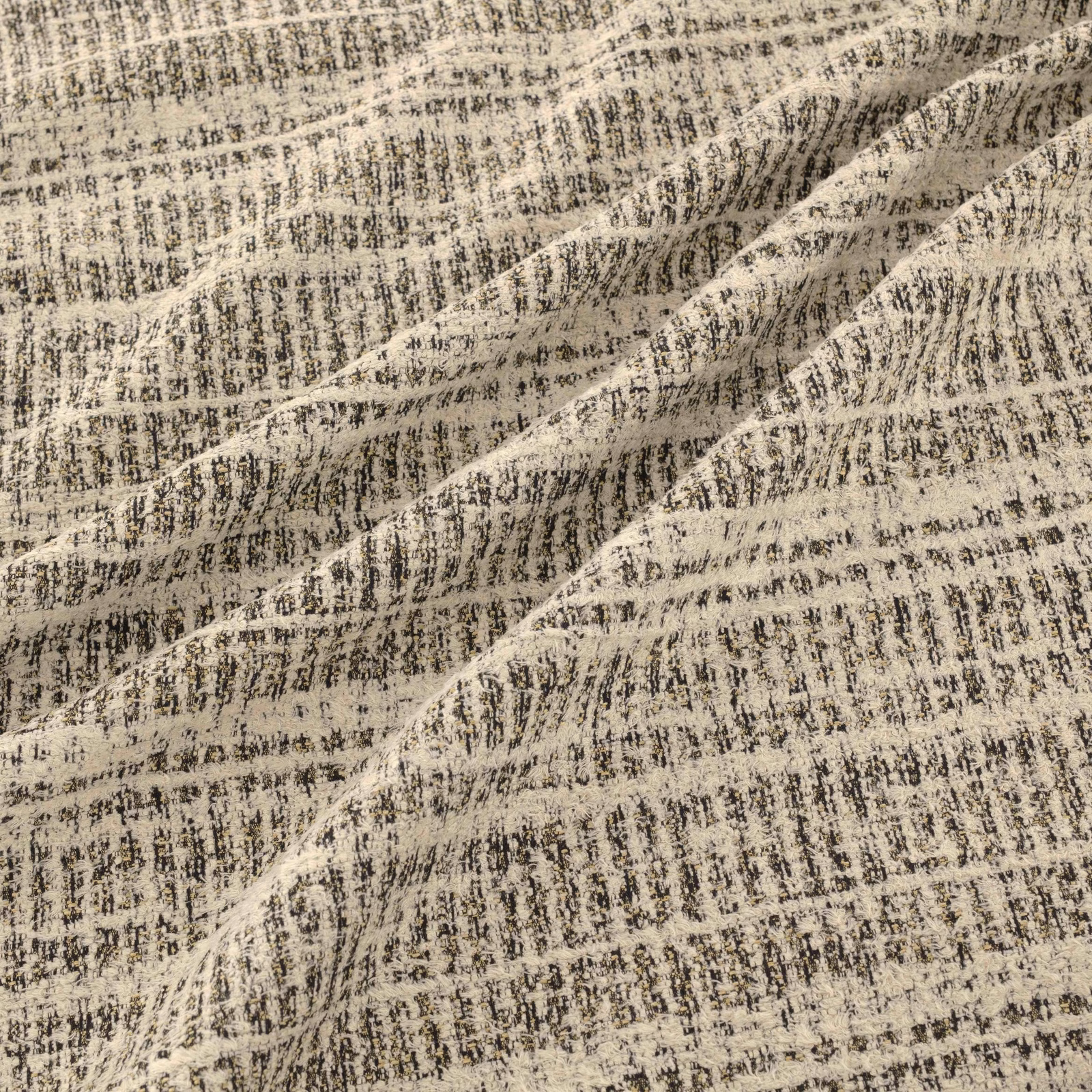 Warm beige woven fabric with charcoal flecks, broken striations and raised folds
