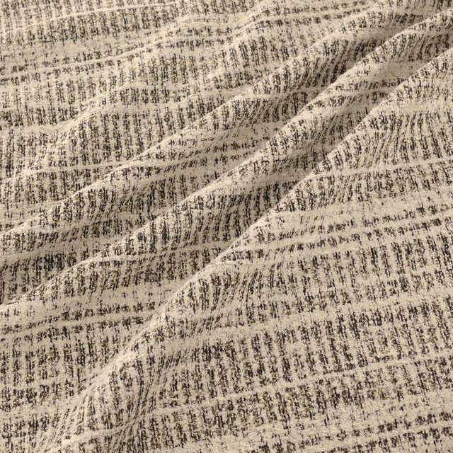 Warm beige woven fabric with charcoal flecks, broken striations and raised folds