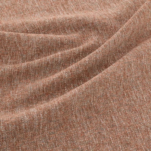 Close-up of warm terracotta woven fabric with pale flecks and softly folded texture
