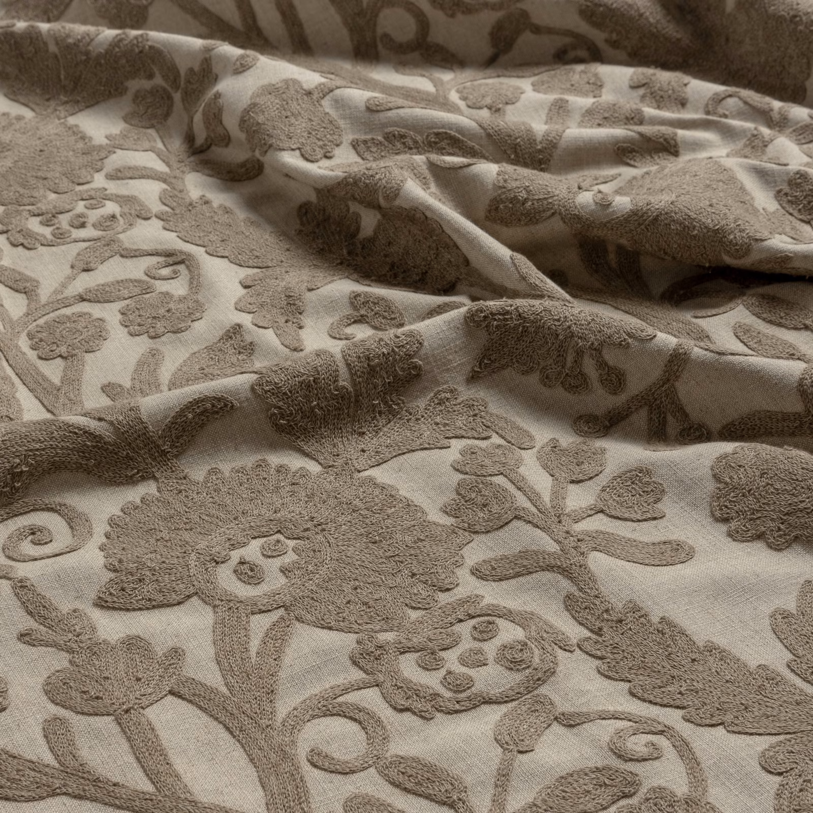 Warm ivory fabric with raised taupe floral, paisley and scrolling motifs