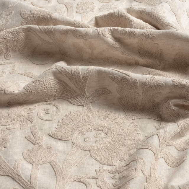 Porcelain-cream fabric with raised floral scrolls and softly folded woven texture