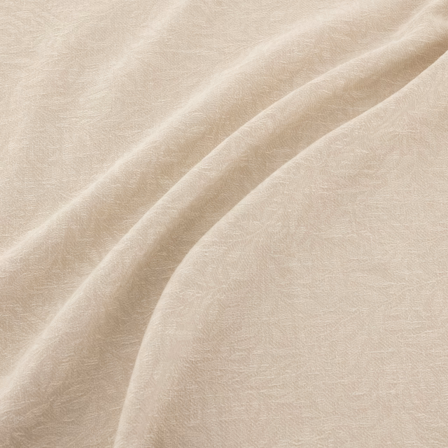 Ivory fabric with subtle tonal filigree texture flowing across soft draped folds