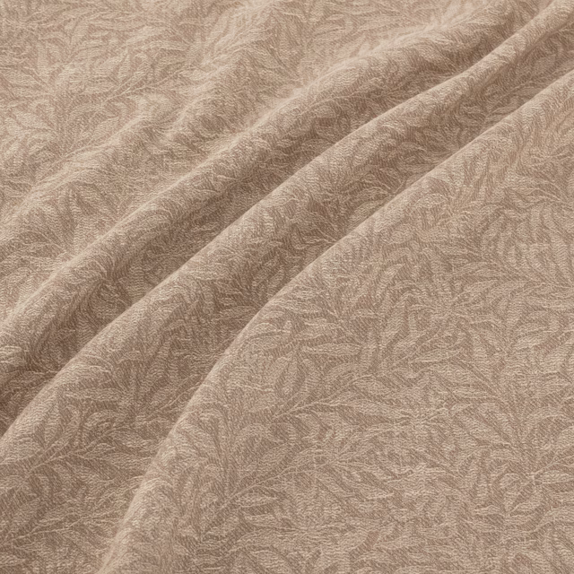 Warm natural taupe fabric with fine leafy filigree texture draped into soft folds