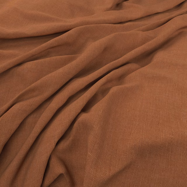 Warm henna terracotta fabric showing a fine plain weave in soft gathered folds