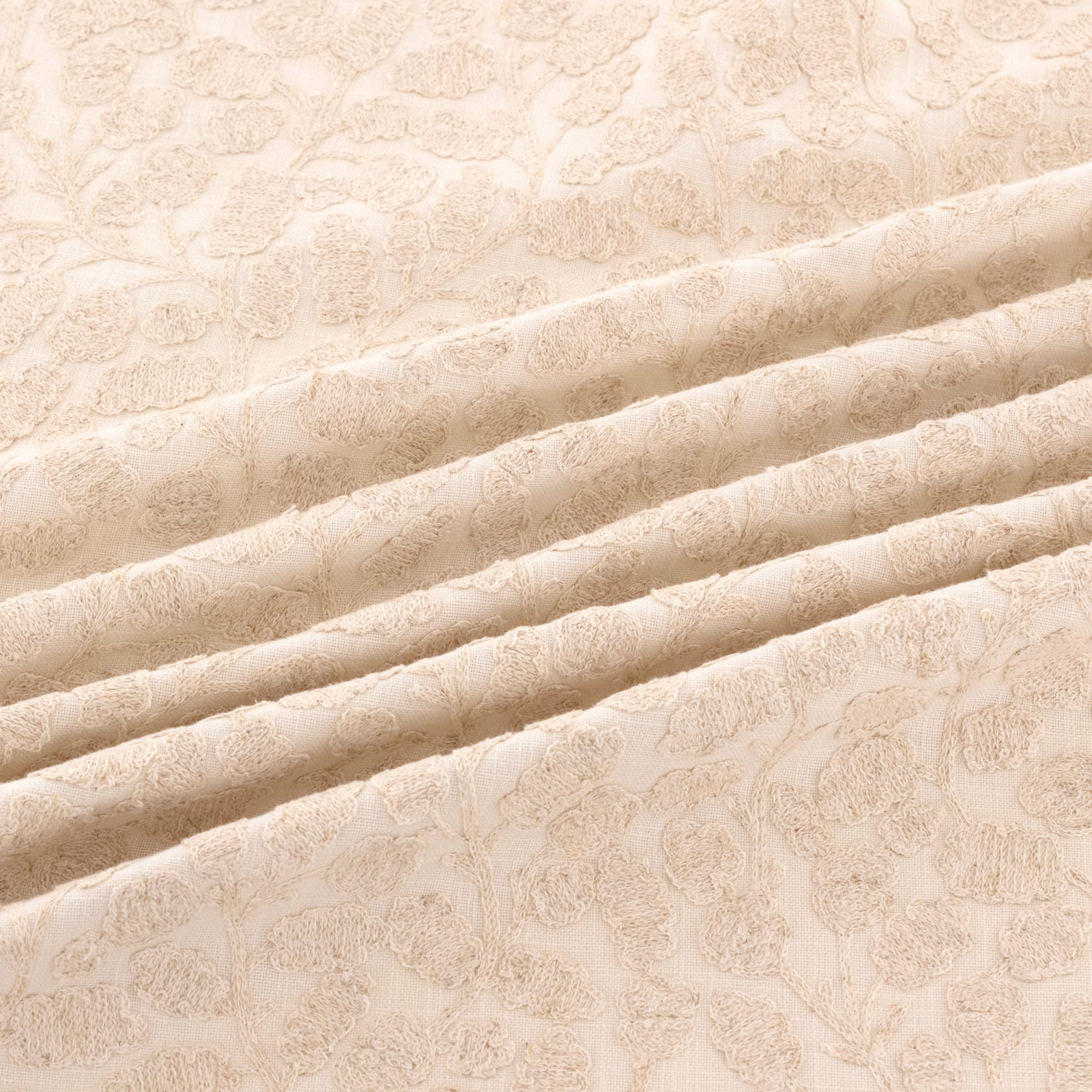 Pale oyster jacquard with raised scrolling floral motifs across folded fabric