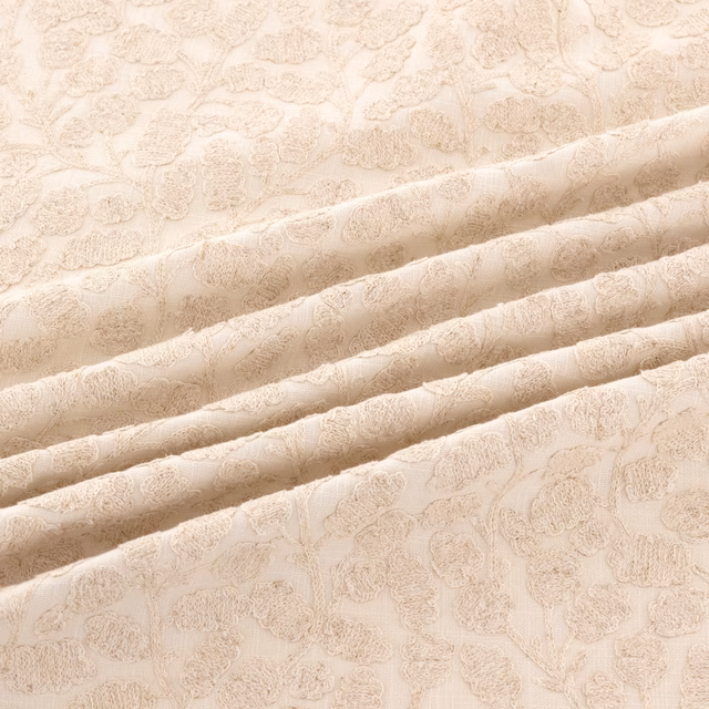 Pale oyster jacquard with raised scrolling floral motifs across folded fabric
