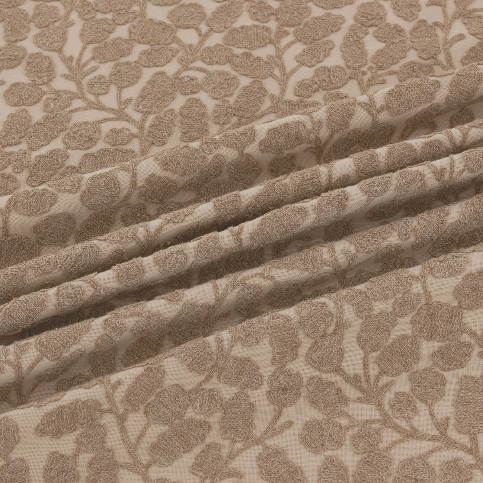 Warm taupe floral-vine textile with textured motifs shown in softly gathered folds