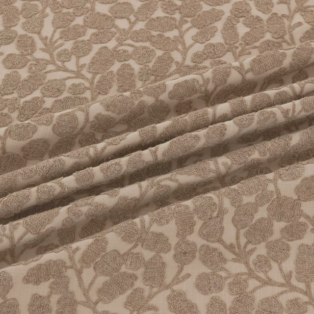 Warm taupe floral-vine textile with textured motifs shown in softly gathered folds