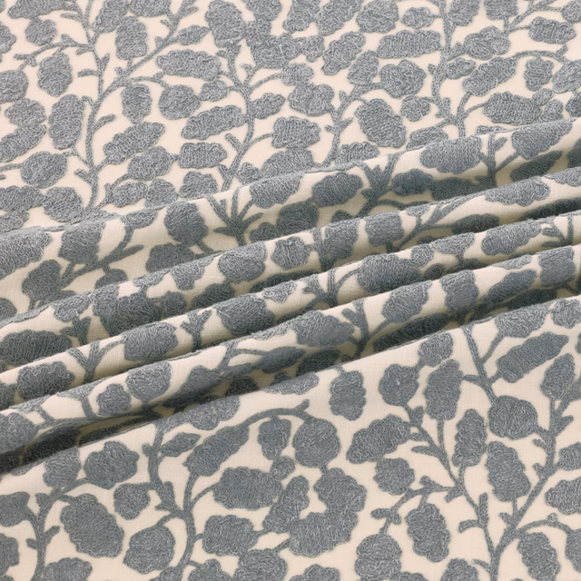 Cool blue-grey leafy branches on ivory fabric, shown in soft textured folds