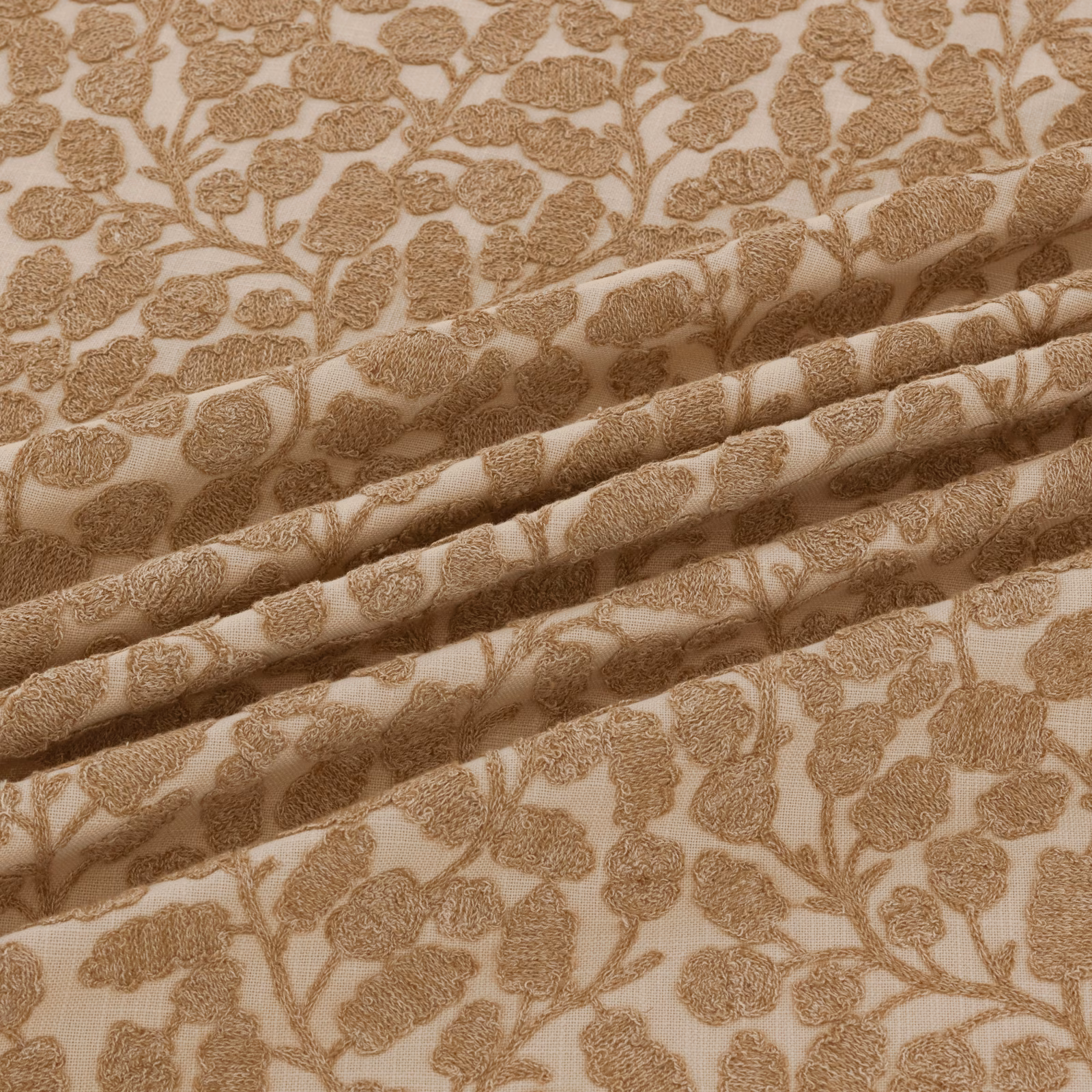 Warm sand-beige woven fabric with raised tan floral vines and folded texture