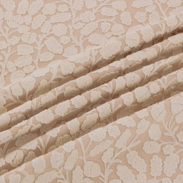 Warm shell-beige floral fabric with raised ivory blossoms and branching stems