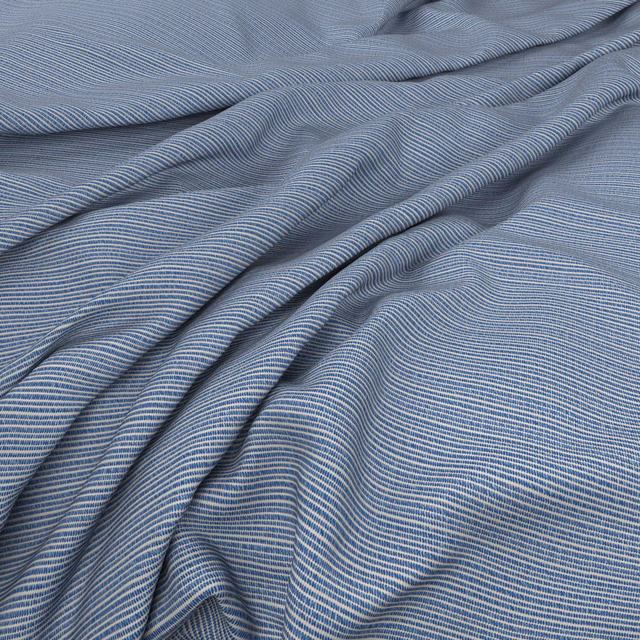 Cool blue-grey fabric with fine striped weave gathered into fluid folds