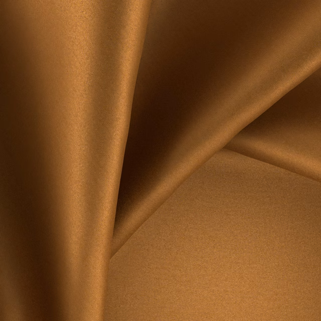 Warm amber-brown glossy fabric forming softly folded, light-catching drapes