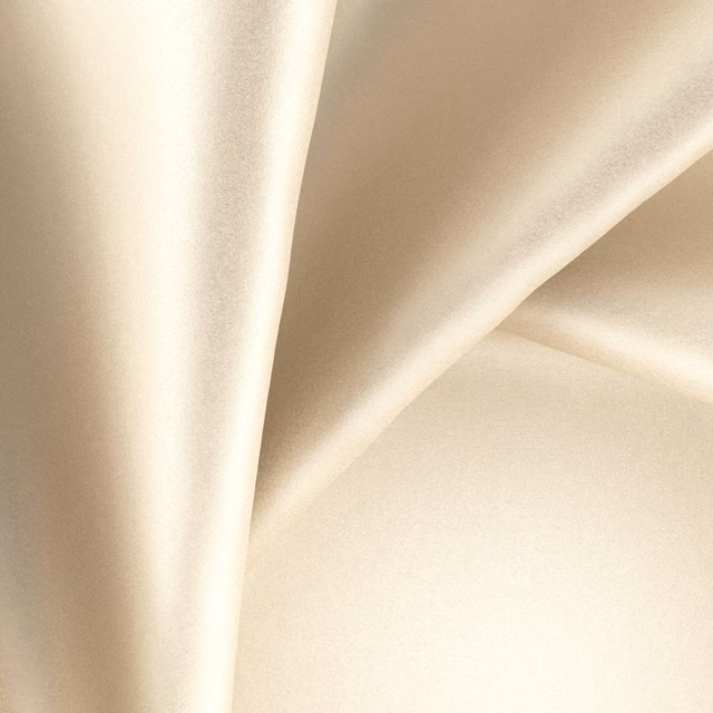 Warm ivory cream fabric folded into flowing shapes with a smooth glossy sheen