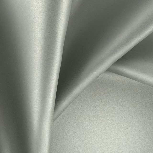 Pale mineral-grey fabric with a softly reflective surface arranged in fluid folds