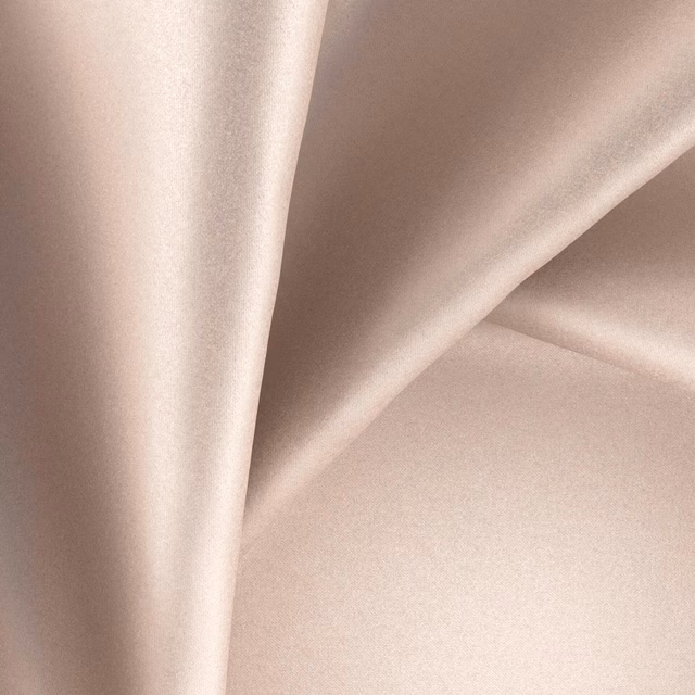 Pale blush-nude glossy textile draped in smooth, softly reflective folds