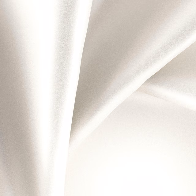 Warm ivory organza draped in smooth folds with luminous satin-like highlights