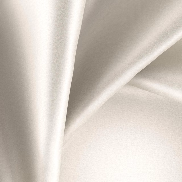 Pale pearl ivory fabric with a smooth glossy surface falling in fluid folds
