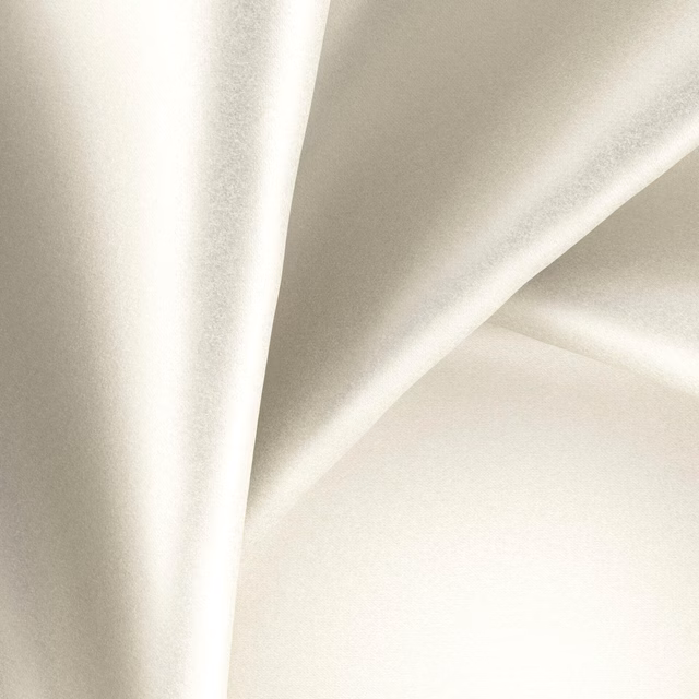 Glossy ivory fabric with a smooth sheen falling in soft, fluid folds