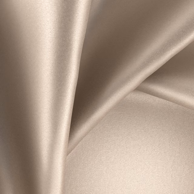 Warm sesame-beige glossy fabric draped in soft folds with satin-like highlights