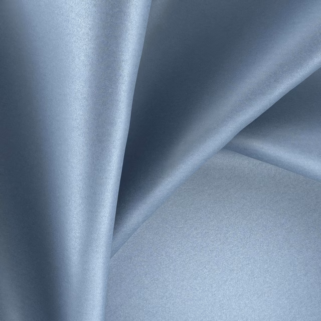 Pale blue-grey glossy textile forming soft, fluid folds with subtle light variation