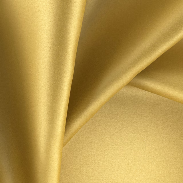 Close view of golden-yellow plain fabric with a smooth lustrous sheen in folds