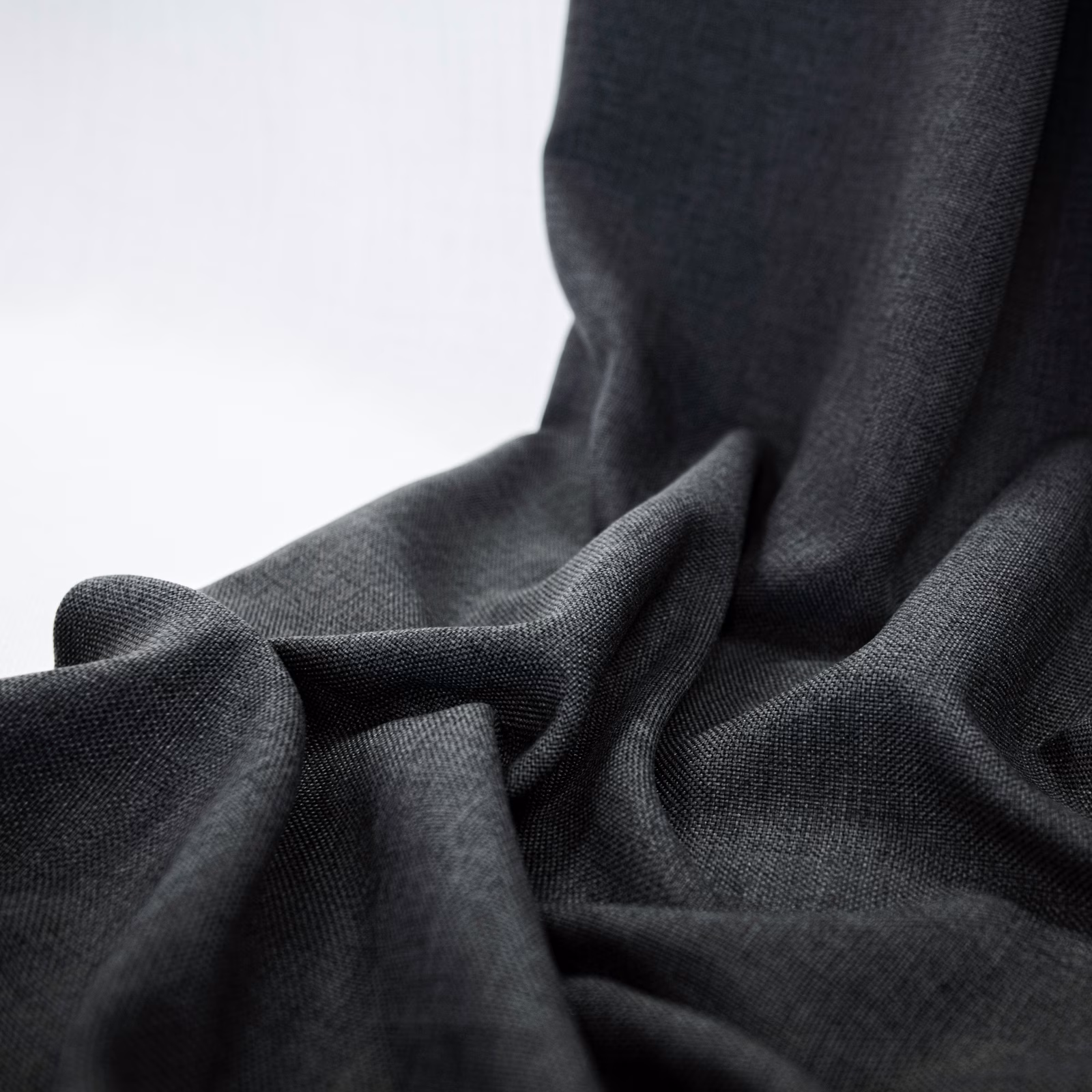 Deep charcoal fine-woven fabric arranged in soft, sculptural folds