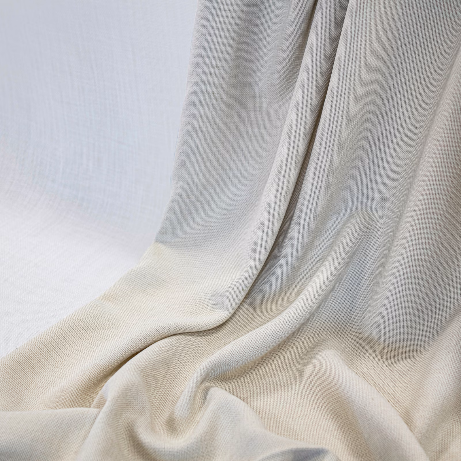 Warm ivory fabric draped in fluid folds, showing a fine woven texture and soft shadows
