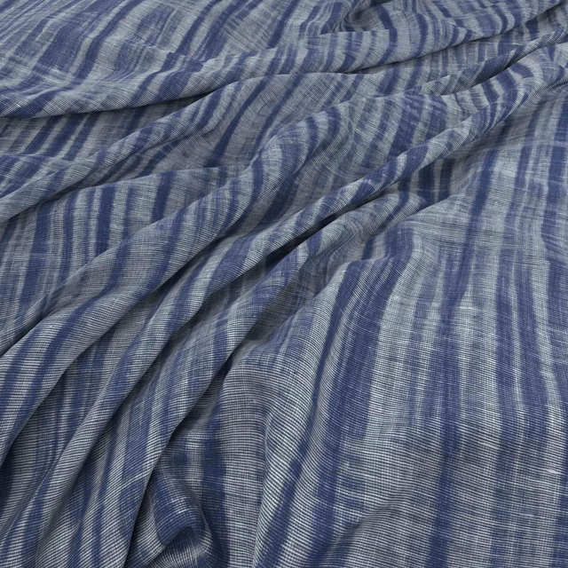 Indigo blue fabric with irregular pale vertical stripes gathered into soft folds