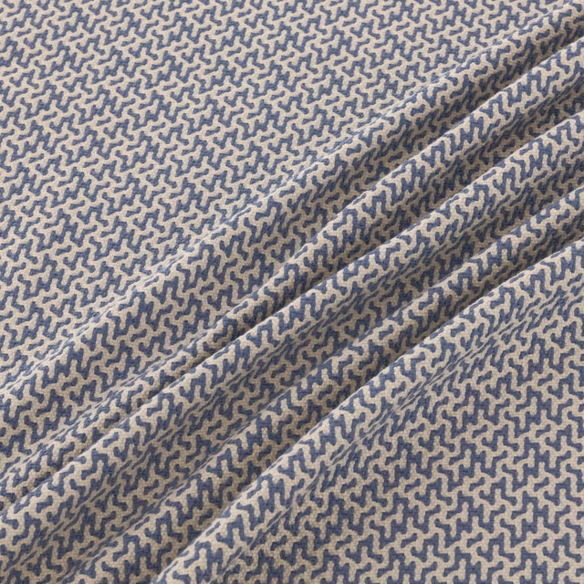 Blue-grey meandering motif on taupe woven fabric, shown folded in close-up