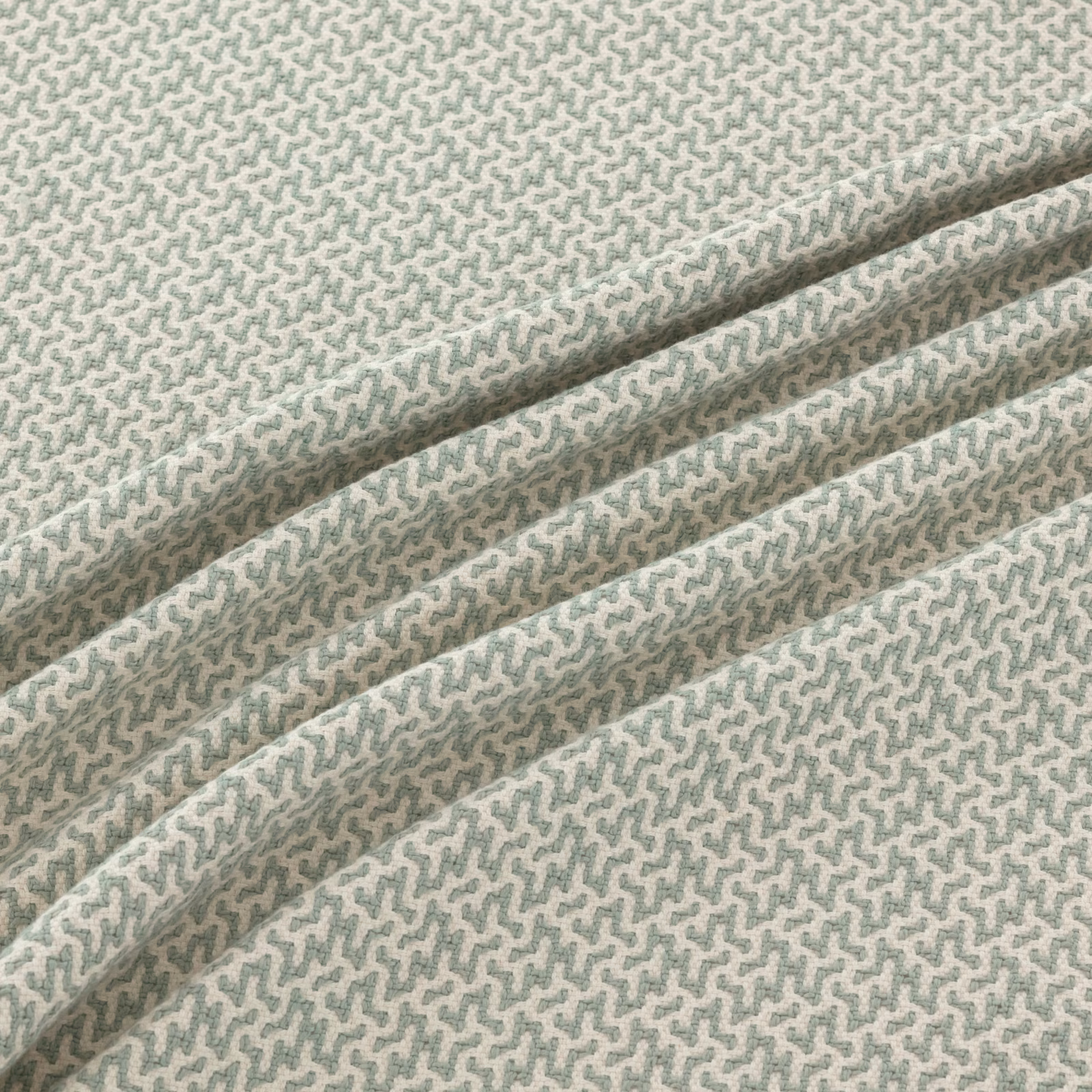 Pale seafoam woven fabric with a fine sage-grey meander motif in soft folds