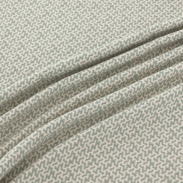 Pale seafoam woven fabric with a fine sage-grey meander motif in soft folds