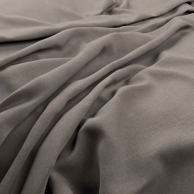 Close-up of cement-grey fabric in fluid folds showing a fine woven texture