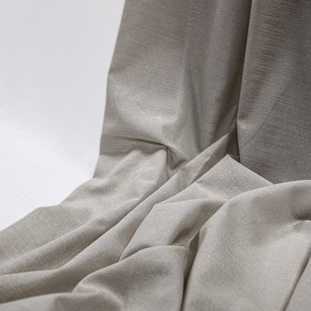 Warm ecru woven textile gathered into fluid folds with a subtle fine horizontal texture