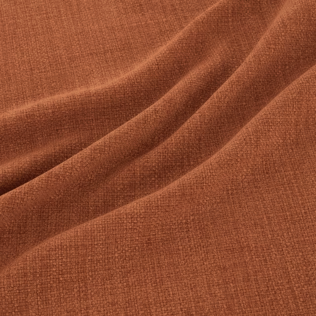 Warm henna rust fabric with a fine tactile weave folded into soft ridges