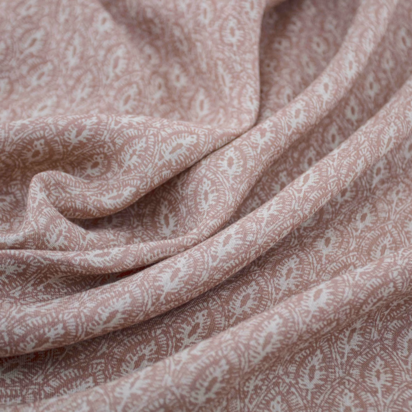 Dusty blush-pink fabric with ivory paisley motifs gathered into soft folds