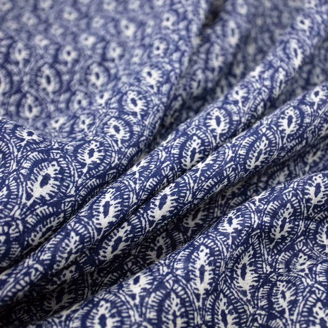 Deep ink-blue fabric with dense ivory paisley and floral motifs folded into soft ridges