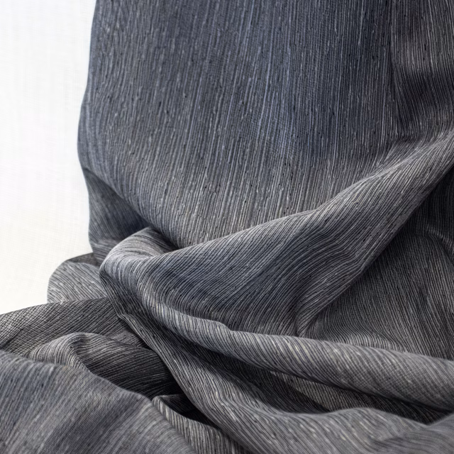 Charcoal-grey textile with fine vertical striations gathered into fluid rippling folds