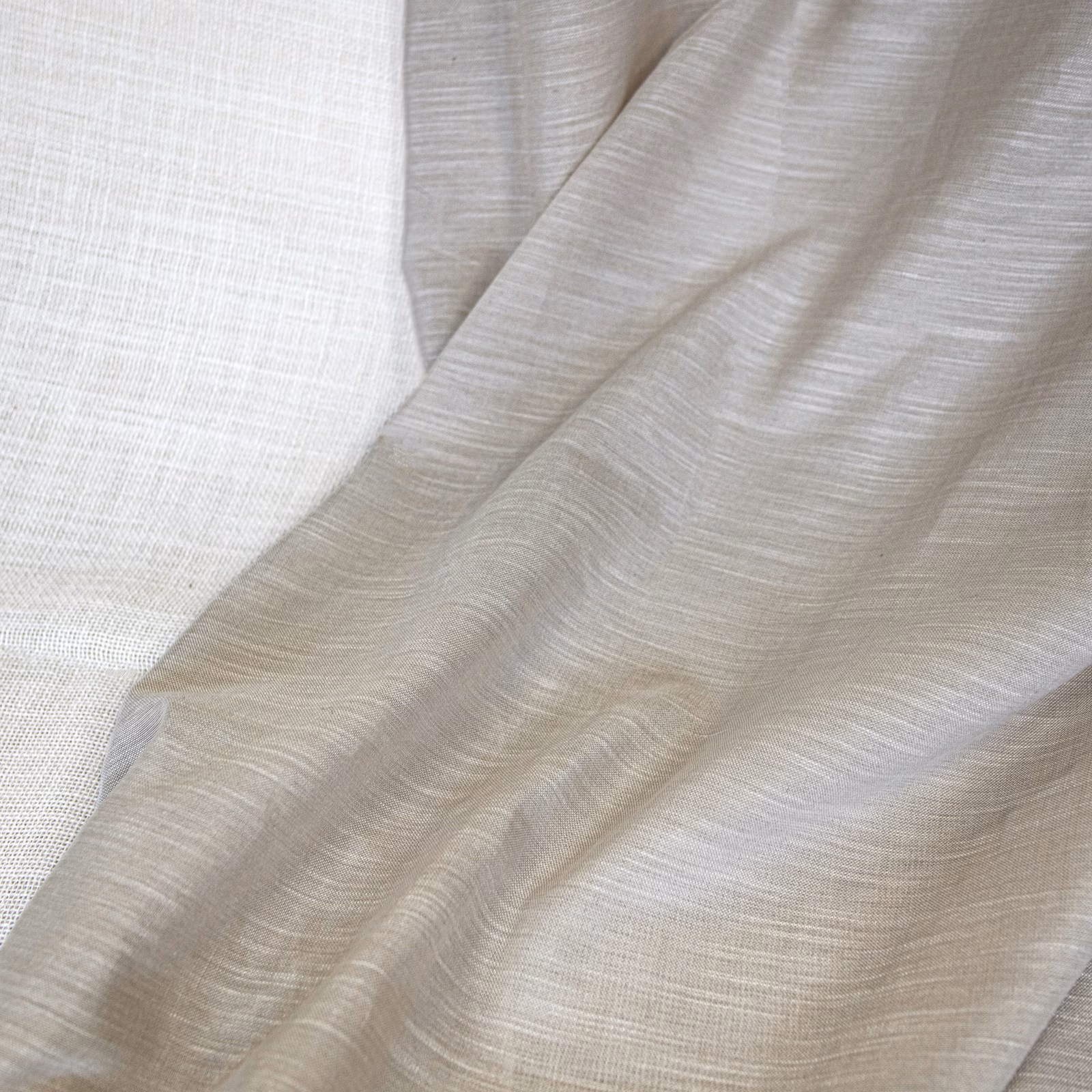 Warm natural greige fabric with fine horizontal slub texture draped in soft folds