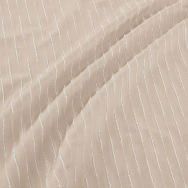 Warm ivory beige fabric with fine irregular white vertical lines and fluid folds