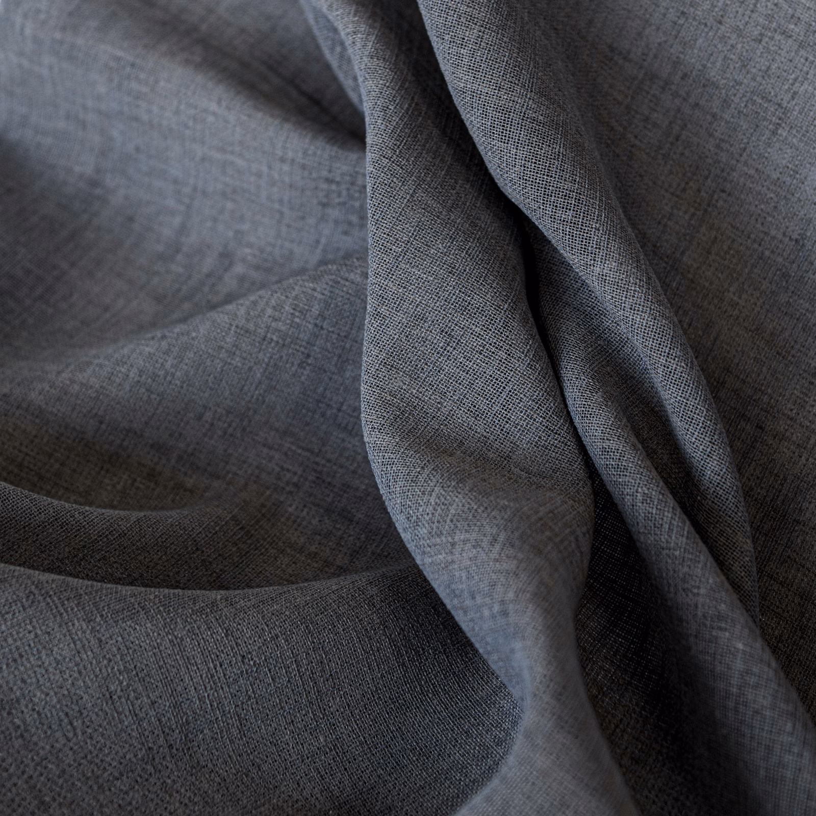 Deep charcoal woven cloth draped in layered folds with a fine crosshatch texture