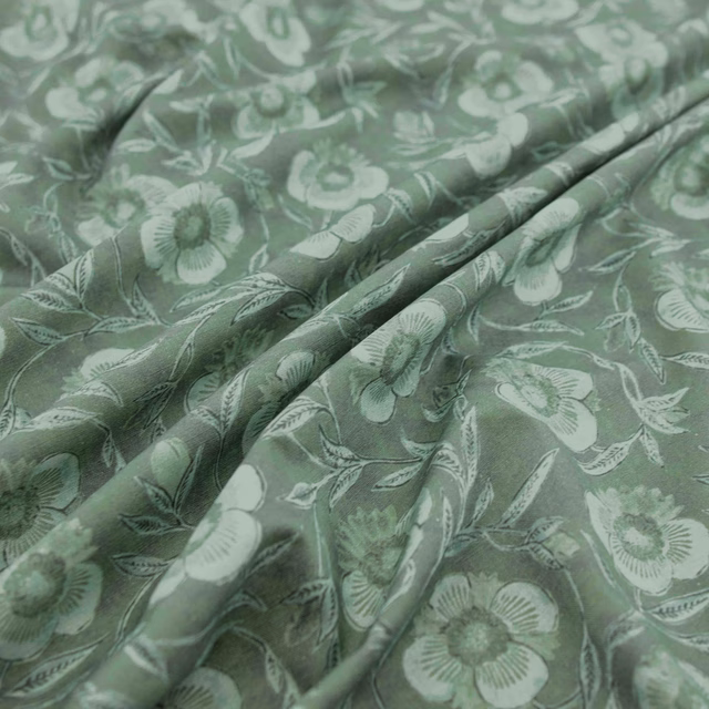 Soft clover-green floral fabric with pale blossoms, leafy stems and flowing folds