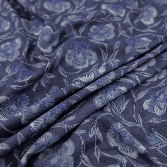 Indigo floral fabric with pale blue-grey blooms and flowing stems in folded cloth