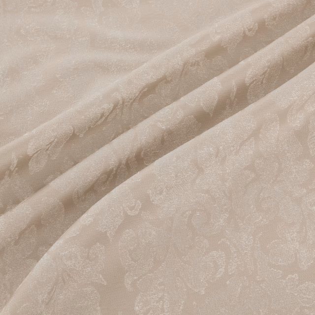 Warm ivory-beige fabric in soft folds with tonal paisley and scrolling motifs