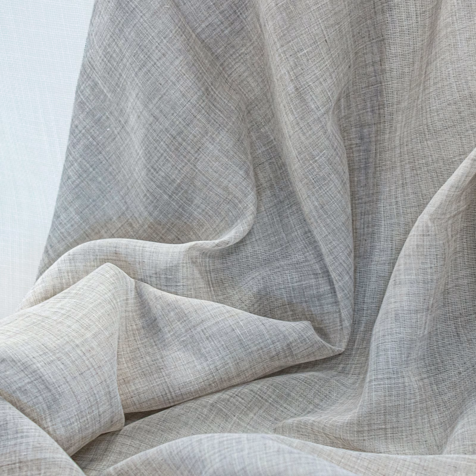 Pale ecru drapery with fine grey crosshatch weave gathered into soft flowing folds