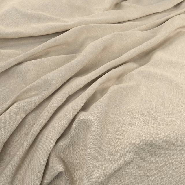 Pale warm-greige plain weave fabric gathered into soft flowing folds