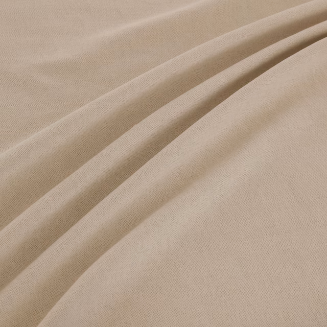 Warm natural-beige plain weave fabric falling in softly gathered folds